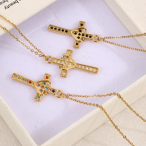 Dettaglio di tre collane a croce con cuore in oro e cristalli neri, bianchi e colorati