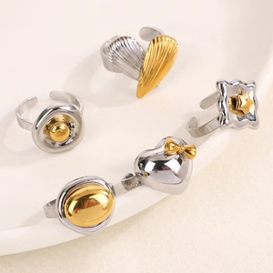 Detail of two-tone adjustable rings with gold heart and star motifs on white ceramic