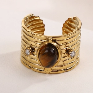 Makroaufnahme eines vergoldeten Retro-Rings mit Tigerauge und Zirkonia auf gehämmerter Ringschiene