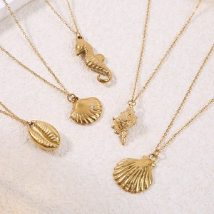 Gold ocean themed necklaces featuring seahorse, shell and conch pendants on white surface