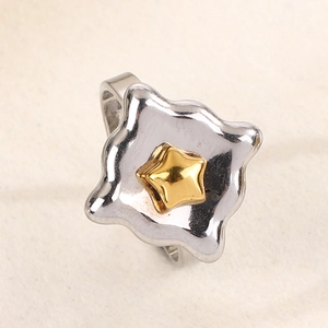 Close-up of a square silver ring with a metallic wavy edge and a golden star detail