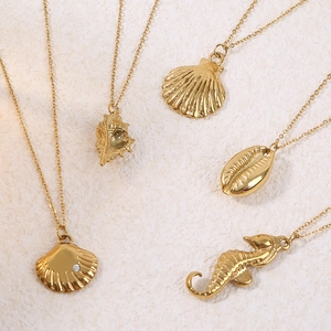 Seahorse and seashell gold-plated ocean theme necklaces on a white stone background