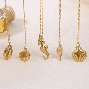 Detail of gold seashell and seahorse pendants on ocean-themed stainless steel necklaces