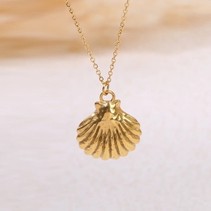 Close-up of golden seashell pendant necklace with detailed texture on fine link chain