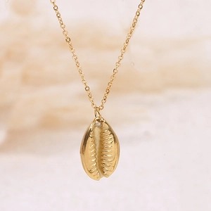 Macro view of a polished golden seashell pendant on a delicate cross chain necklace