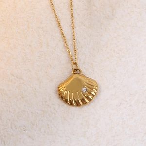 Macro detail of golden seashell pendant with radial texture and sparkling zircon inlay