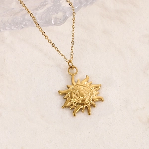 Gros plan d'un collier pendentif soleil plaqué or 14K sur une surface en pierre naturelle