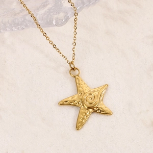 Gros plan détaillé du pendentif étoile de mer doré avec texture martelée sur fond mat