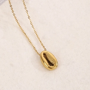 Gros plan du collier pendentif coquillage plaqué or avec texture détaillée sur chaîne fine