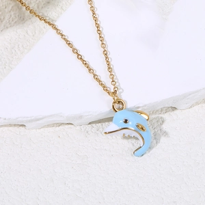 Close-up of golden dolphin pendant with blue enamel on a minimalist white stone background