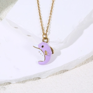 Detail of purple enamel dolphin pendant on a thin gold chain against white stone texture