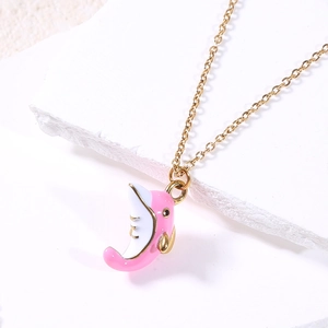 Detail of pink and white enamel dolphin pendant on a gold chain over stone texture