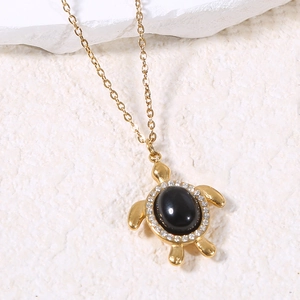 Gros plan du collier tortue avec pierre précieuse noire et strass blancs