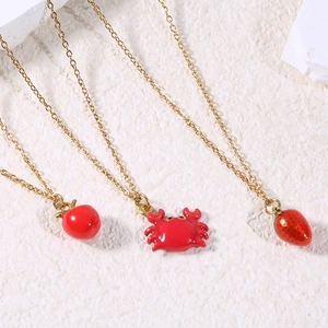 Detail of red enamel fruit and crab pendants on delicate gold chain necklaces