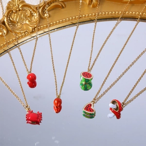 Detail of gold-plated necklaces with watermelon and strawberry enamel charms and reflection