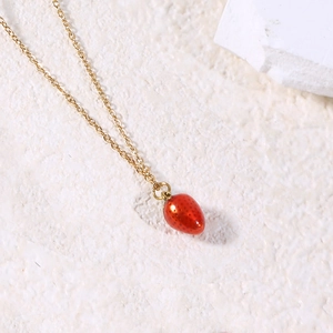 Detailed close-up of a vibrant red strawberry pendant on a delicate gold link chain necklace