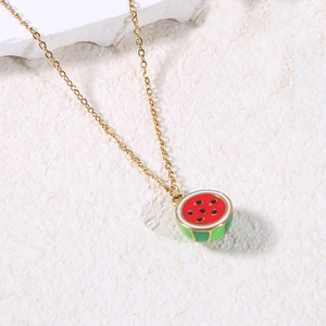 Macro detail of watermelon pendant with red enamel seeds on a textured stone surface