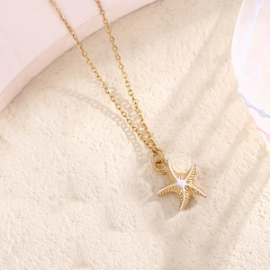 Detail of starfish pendant necklace with white enamel finish on a golden cable chain