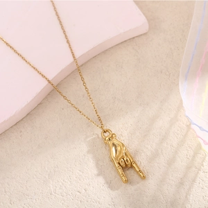 Vue détaillée du pendentif geste de la main rock doré sur une fine chaîne de collier