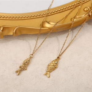 Détail macro de pendentifs carpe koï dorés sur chaîne fine sur cadre vintage