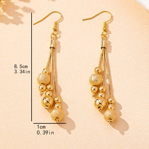 Gold triple-strand beaded tassel earrings featuring sandblasted and polished spheres