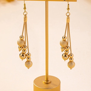 Three-strand gold tassel earrings with polished and frosted beads on a display stand