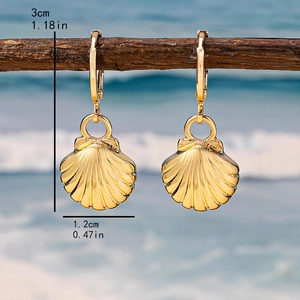 Elegant gold shell dangle earrings on a branch with a beach background, 3cm in height