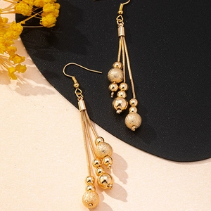 Close-up of golden tassel earrings featuring polished beads and matte textured spheres