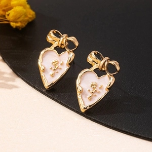 Detail of vintage heart bow earrings with gold rose inlay and pink enamel finish