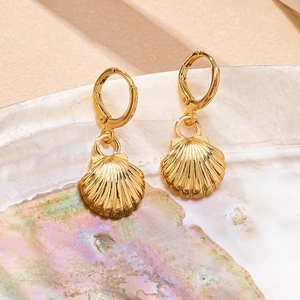 Macro shot of gold scallop shell dangle earrings with textured seashell details
