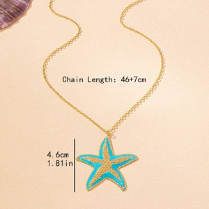 Gold starfish necklace with blue enamel pendant on beach sand background, 46cm length