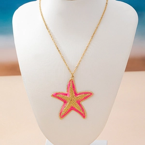Detail of pink starfish pendant with gold beaded texture on a minimalist gold chain