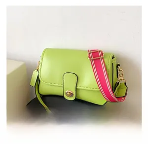 Détail d'un sac carré vert fluo avec fermoir doré et large bandoulière rayée rose