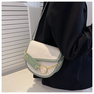 Detail of white crocodile pattern saddle bag with green trim and gold chain accents