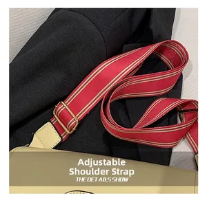 Détail de la bandoulière tissée à rayures rouges et vertes avec boucle dorée et cuir beige