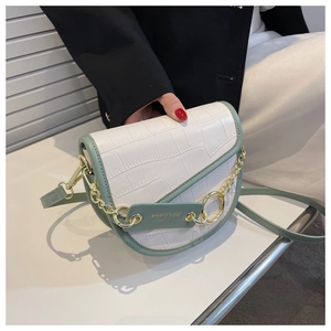 Detail of white crocodile pattern saddle bag with green strap and gold chain strap handle