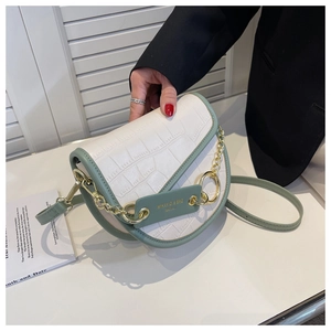 Detail view of contrast saddle bag featuring green leather and white croc pattern