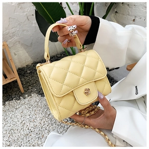 Detail of yellow quilted mini bag with gold flower lock and chain strap
