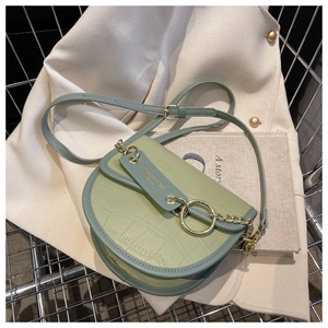 Detail of light green saddle bag with crocodile skin texture and gold chain link accents