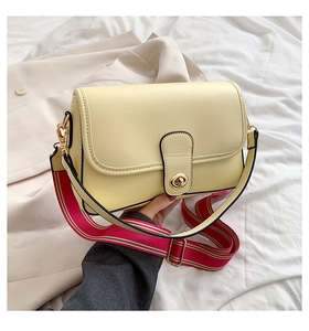Détail du sac bandoulière en cuir PU jaune clair avec une sangle en tissu rayé coloré