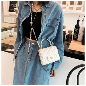 Detailed view of white quilted mini bag with gold flower twist lock and chain strap