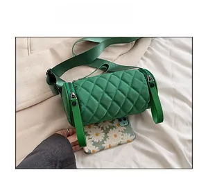 Green quilted nylon cylinder bag size comparison with a smartphone on white cloth