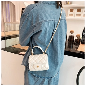 Detailed view of white quilted mini cloud bag with gold floral clasp on a model