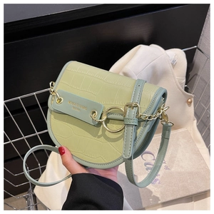 Detail of light green saddle bag with faux crocodile texture and golden metal ring