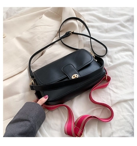 Détail du sac bandoulière en cuir noir avec fermoir doré et bandoulière tissée