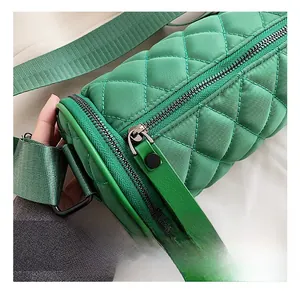 Detail showing green quilted nylon cylinder bag with wide strap and black zipper