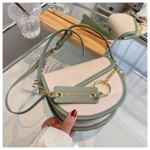Detail of pink faux crocodile saddle bag with green trim and gold chain accents