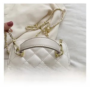 Detail of cream quilted mini crossbody bag featuring gold chain and soft top handle