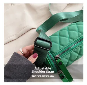 Detail showing the adjustable wide fabric shoulder strap on a green quilted cylinder bag