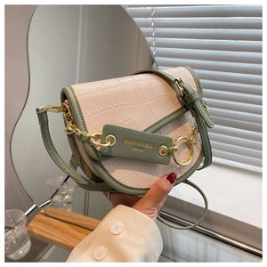 Detailed macro view of cream crocodile texture leather bag with olive green trim and gold chain